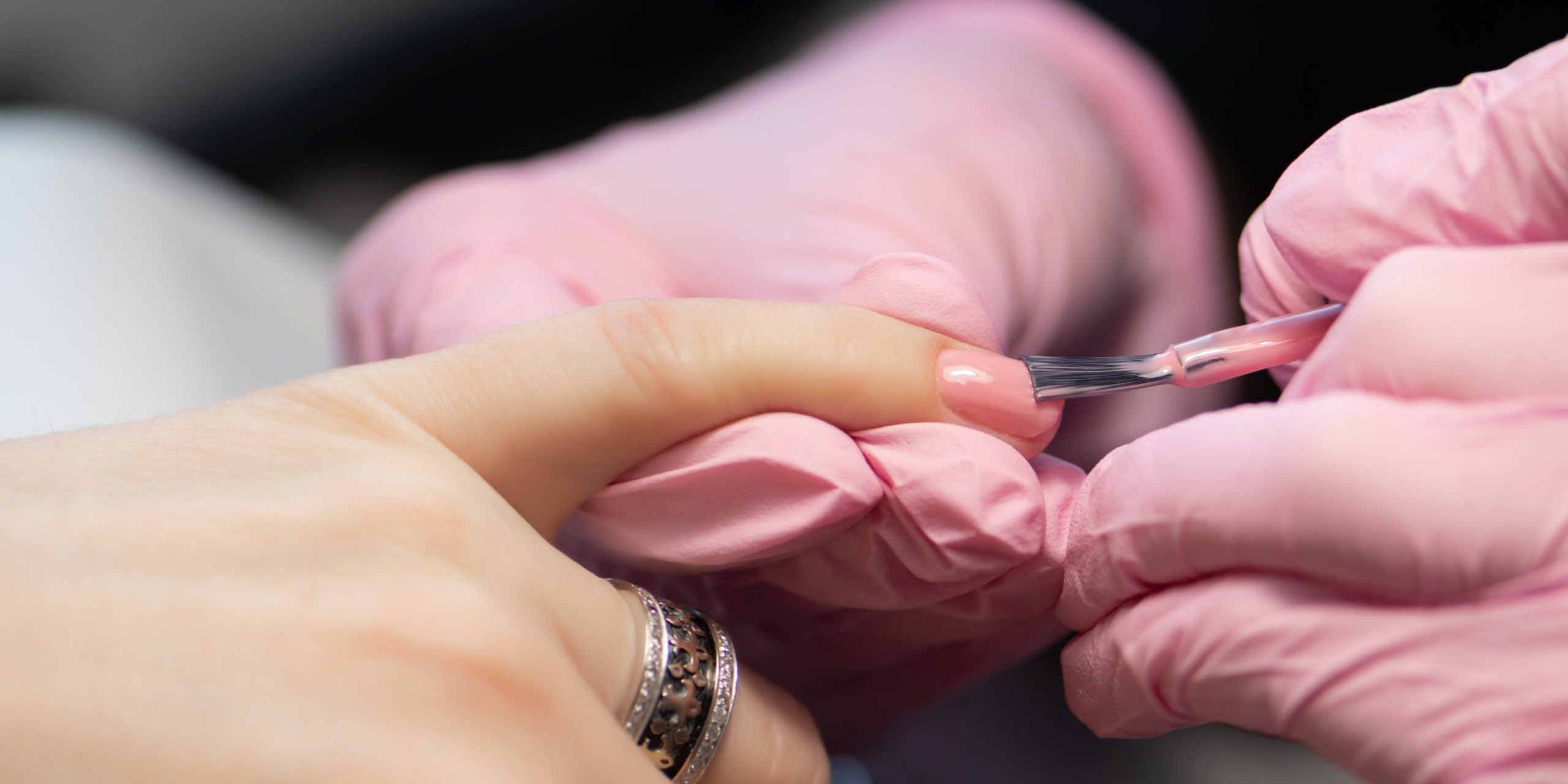 Manicurist doing gel nail design for client, close up.